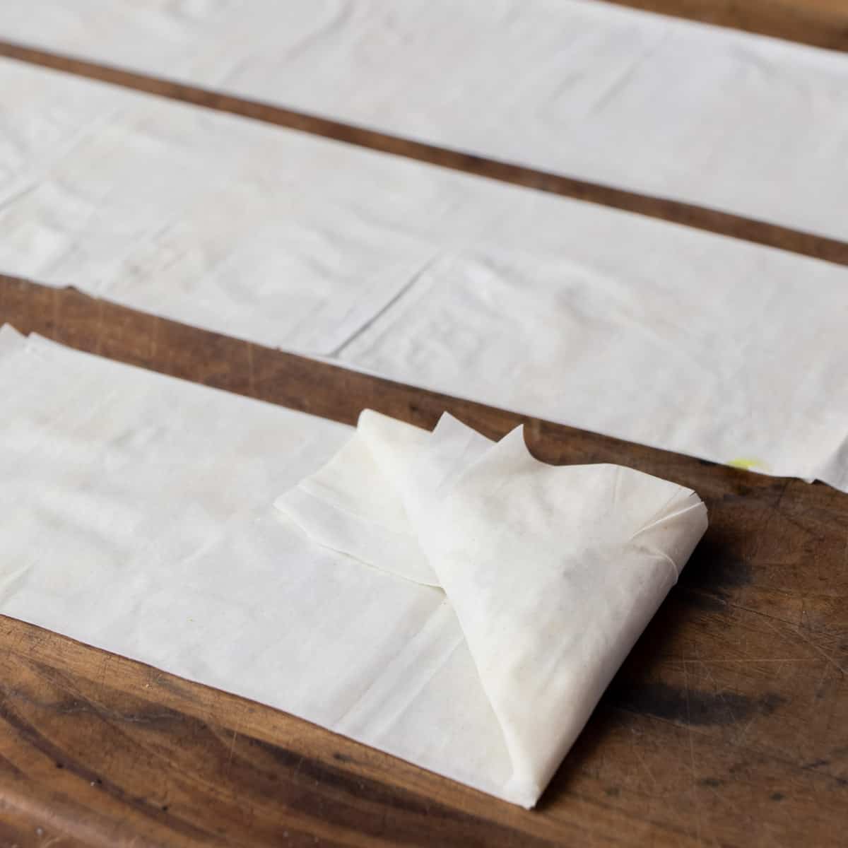 Folding phyllo paper into a stuffed triangle.
