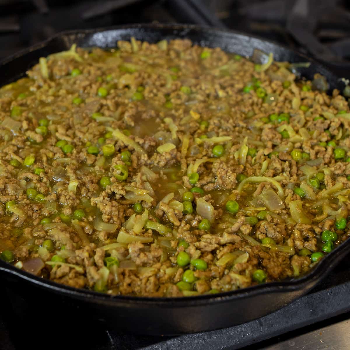 Curry beef and peas in a cast iron skillet.