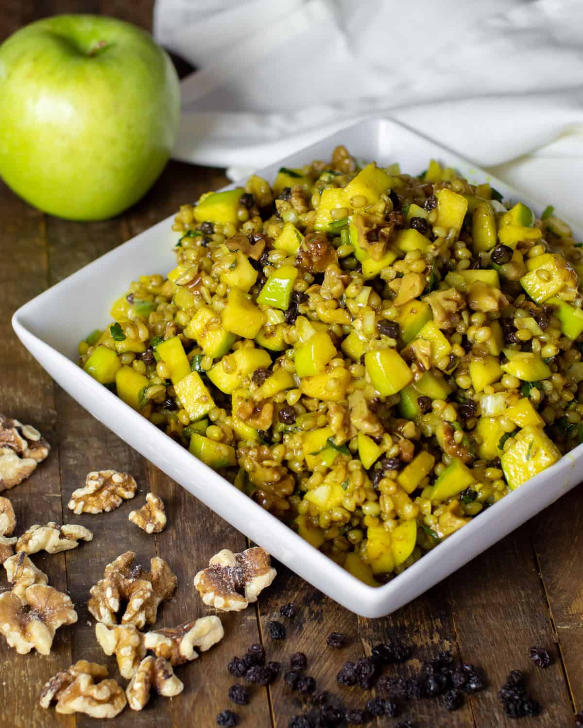 Overhead picture of a salad surrounded by a Granny Smith apple, walnuts, and currants.