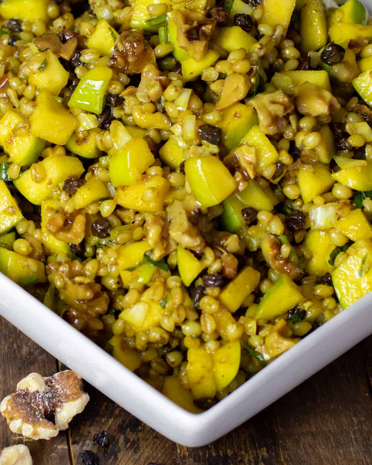 Close up picture of a salad with wheat berries, apple, currants and nuts.