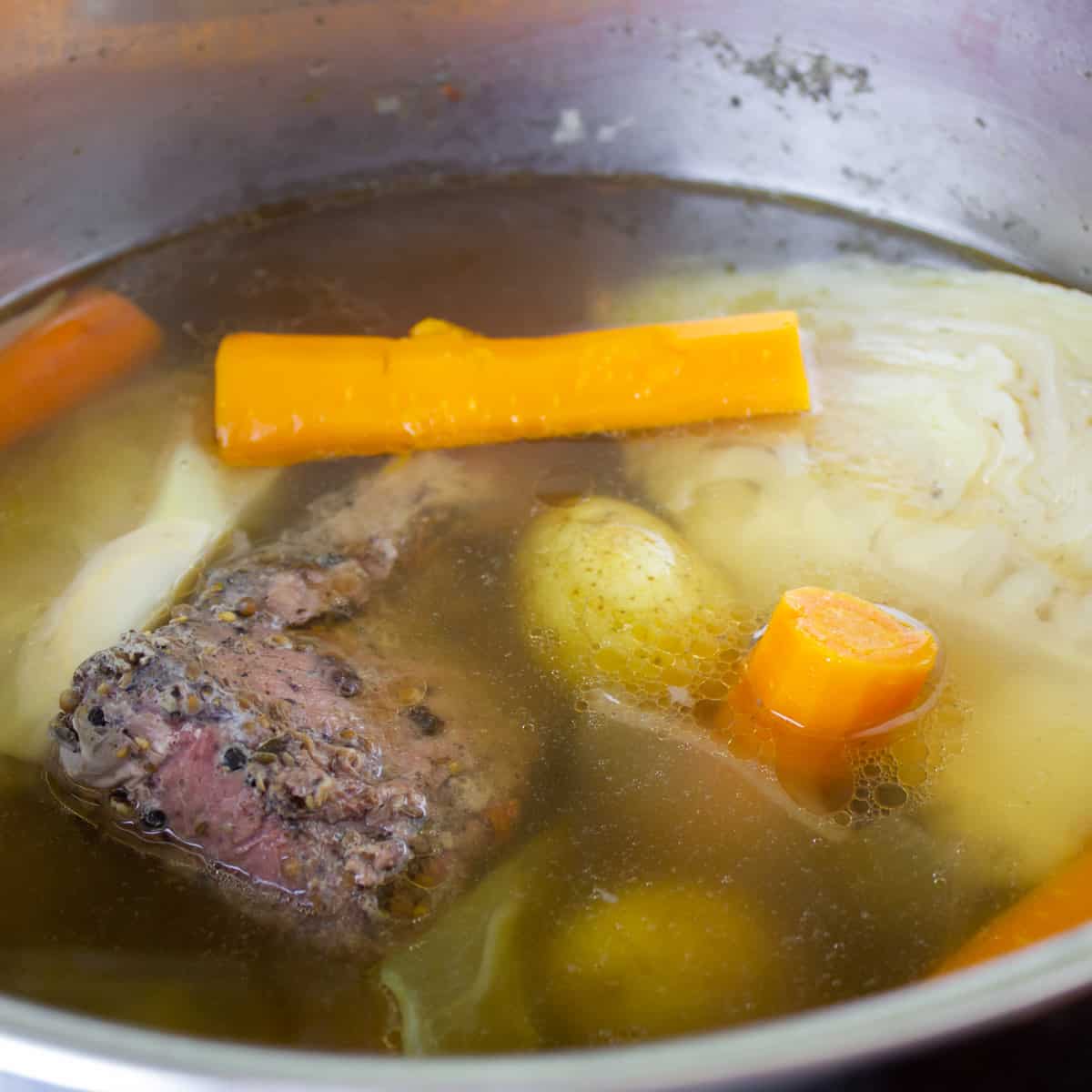 Corned beef and vegetables boiling in a big pot.