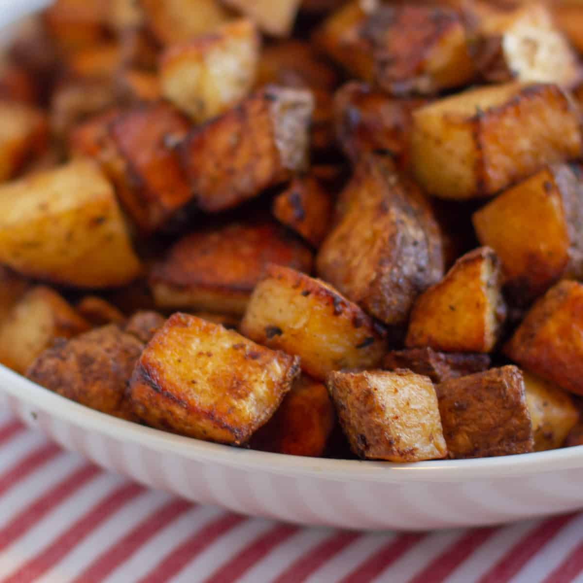 Close up picture of roasted potatoes in a white bowl.