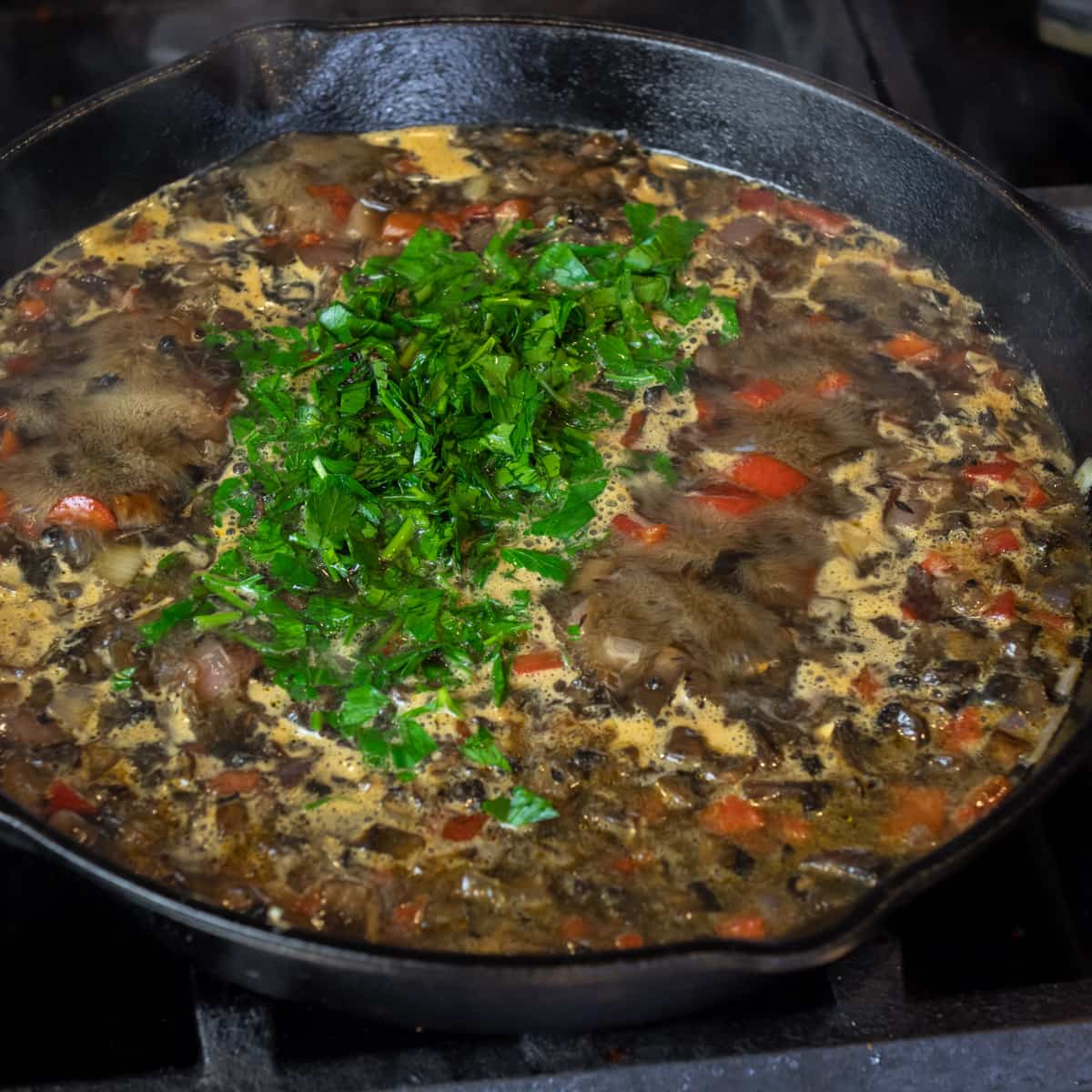 Minced parsley in a skillet with broth and other vegetables.