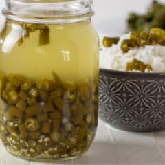 A jar full of pickled green peppers.