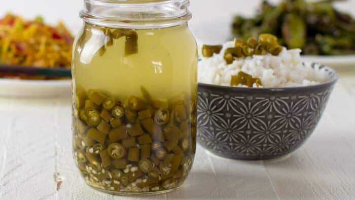 A jar full of pickled green peppers.