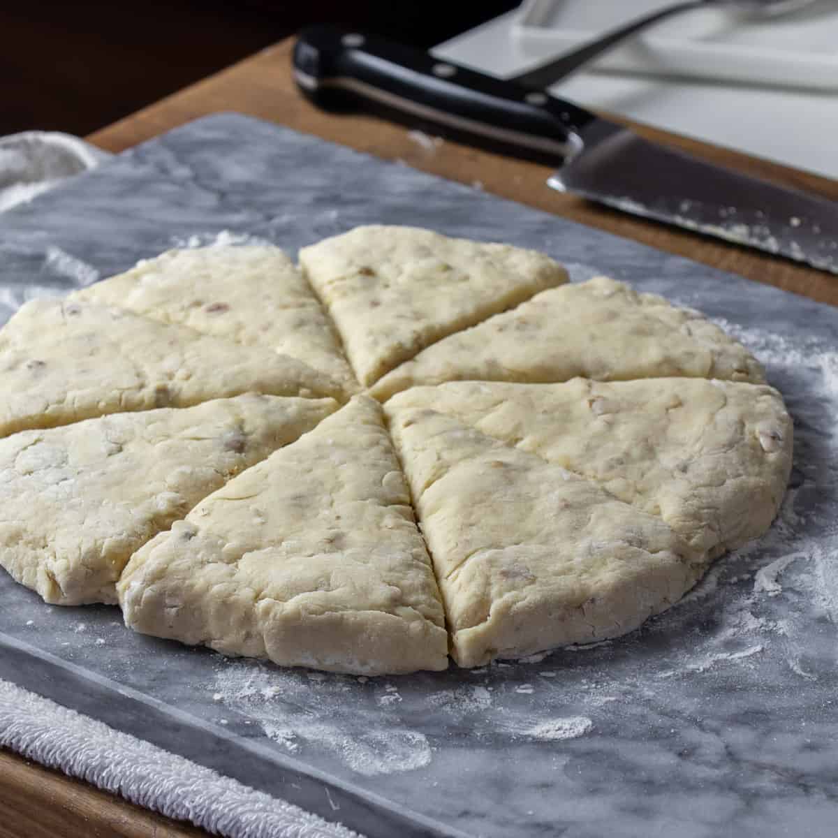 Scones shaped and cut on a marble pastry board.