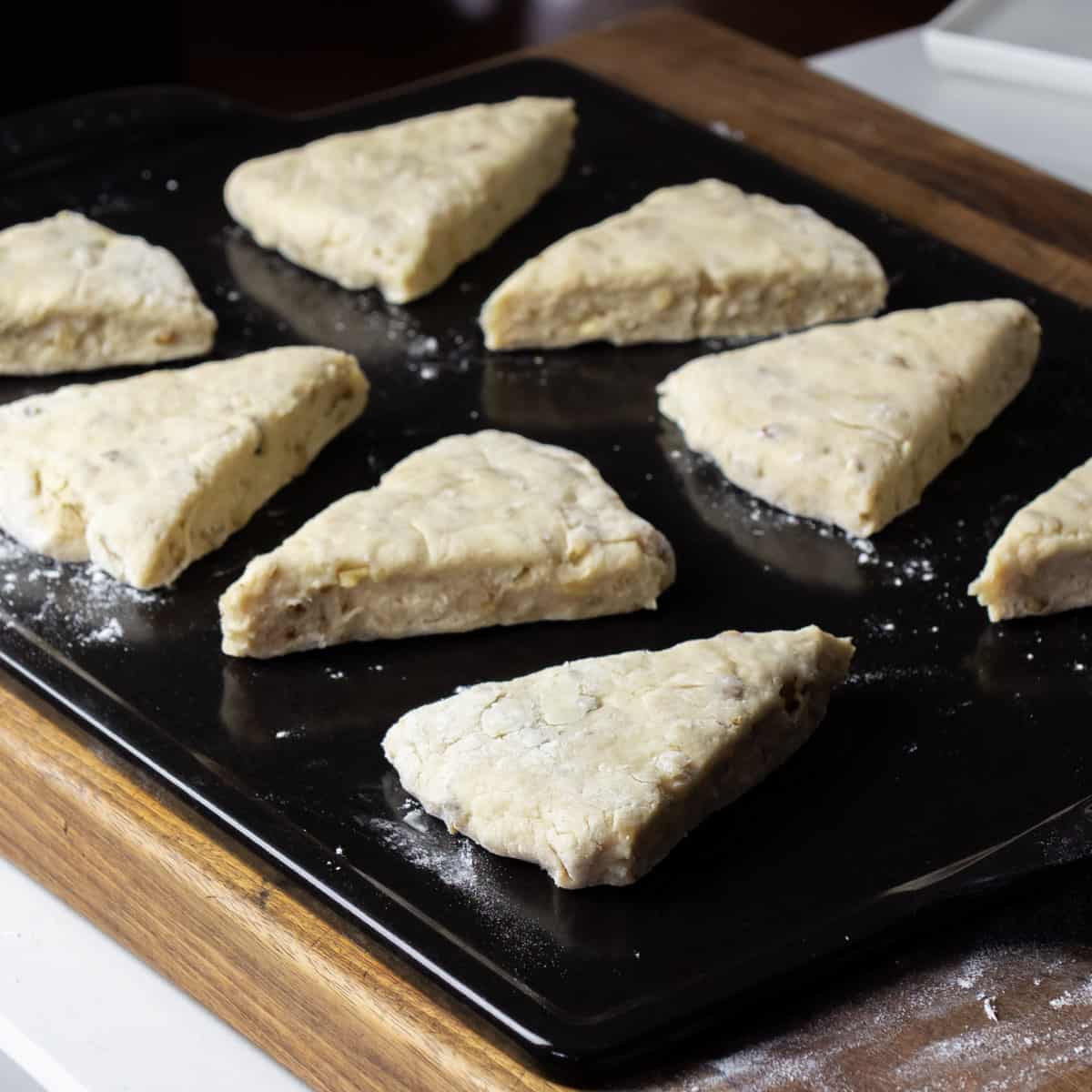 Raw scones on a pizza stone ready to go in the oven.