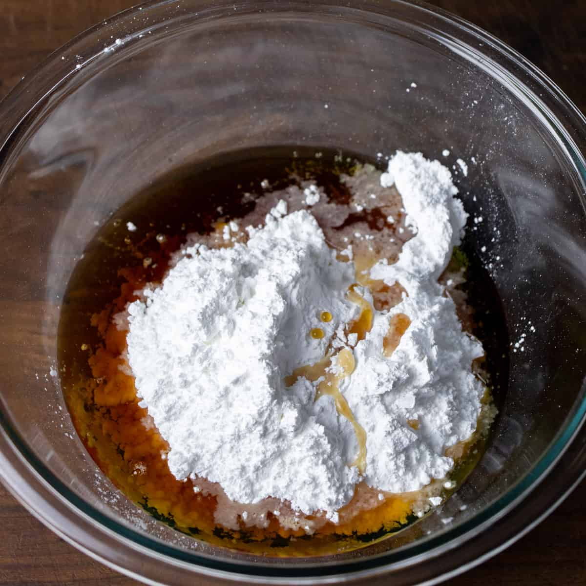 Icing sugar and maple syrup in a glass mixing bowl.