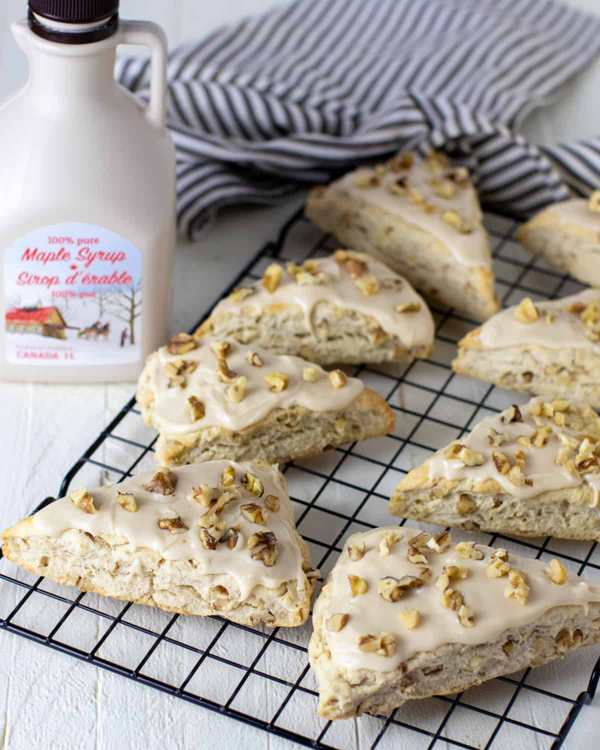 Fresh baked scones next to a jug of maple syrup.