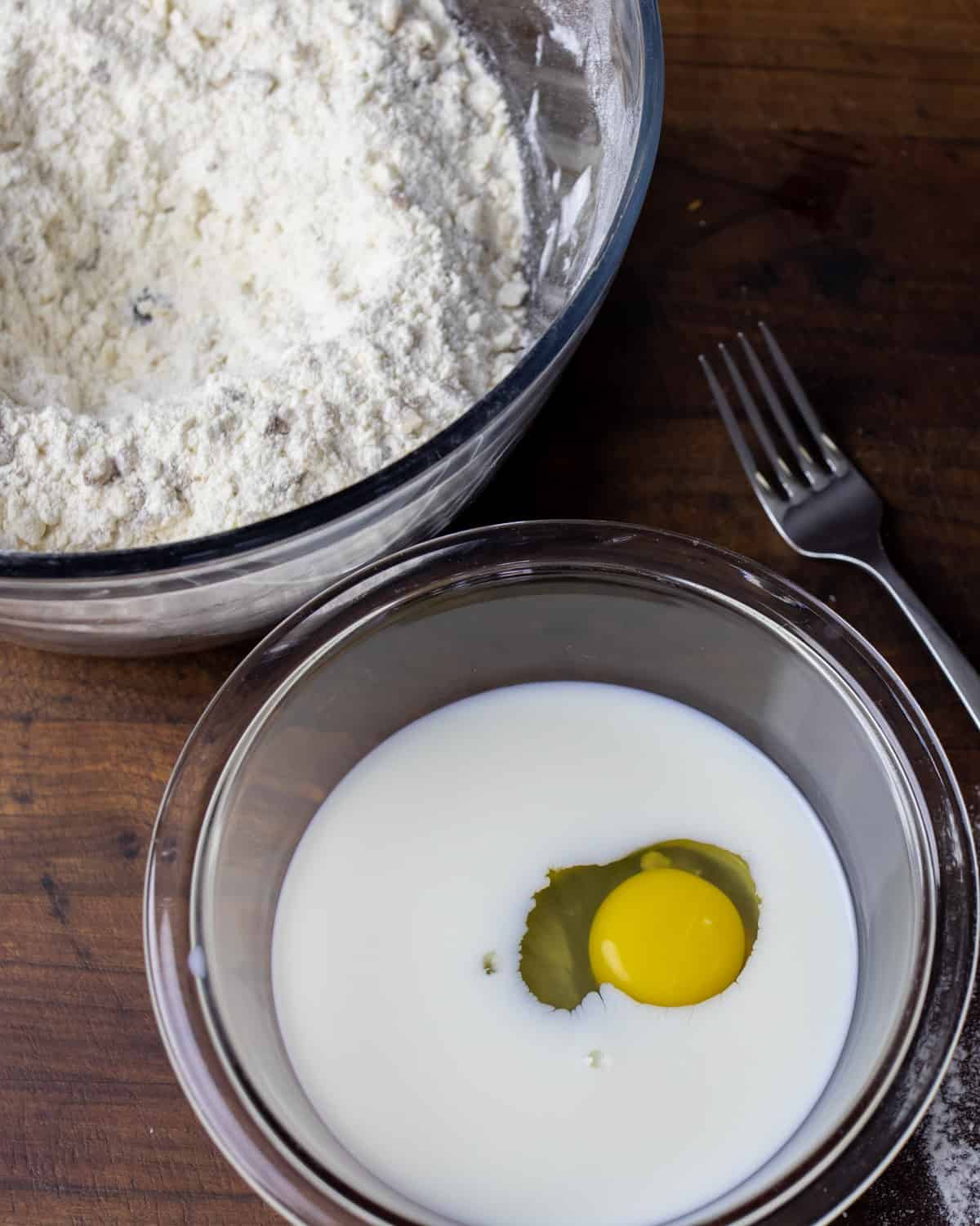 An egg, in a small glass bowl with milk and maple syrup.