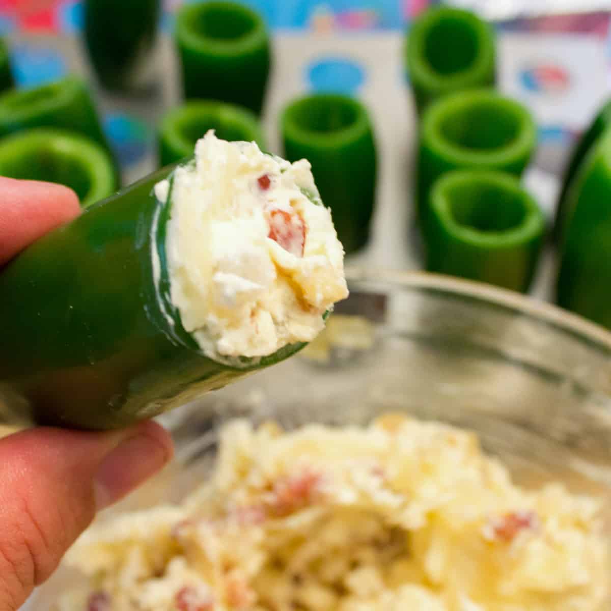 A cored jalapeño pepper being stuffed with a cream cheese and chorizo mixture.