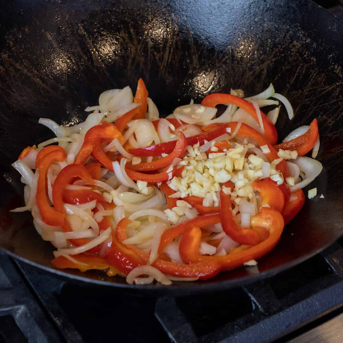 Sliced onion and pepper with minced garlic sautéing in a wok.