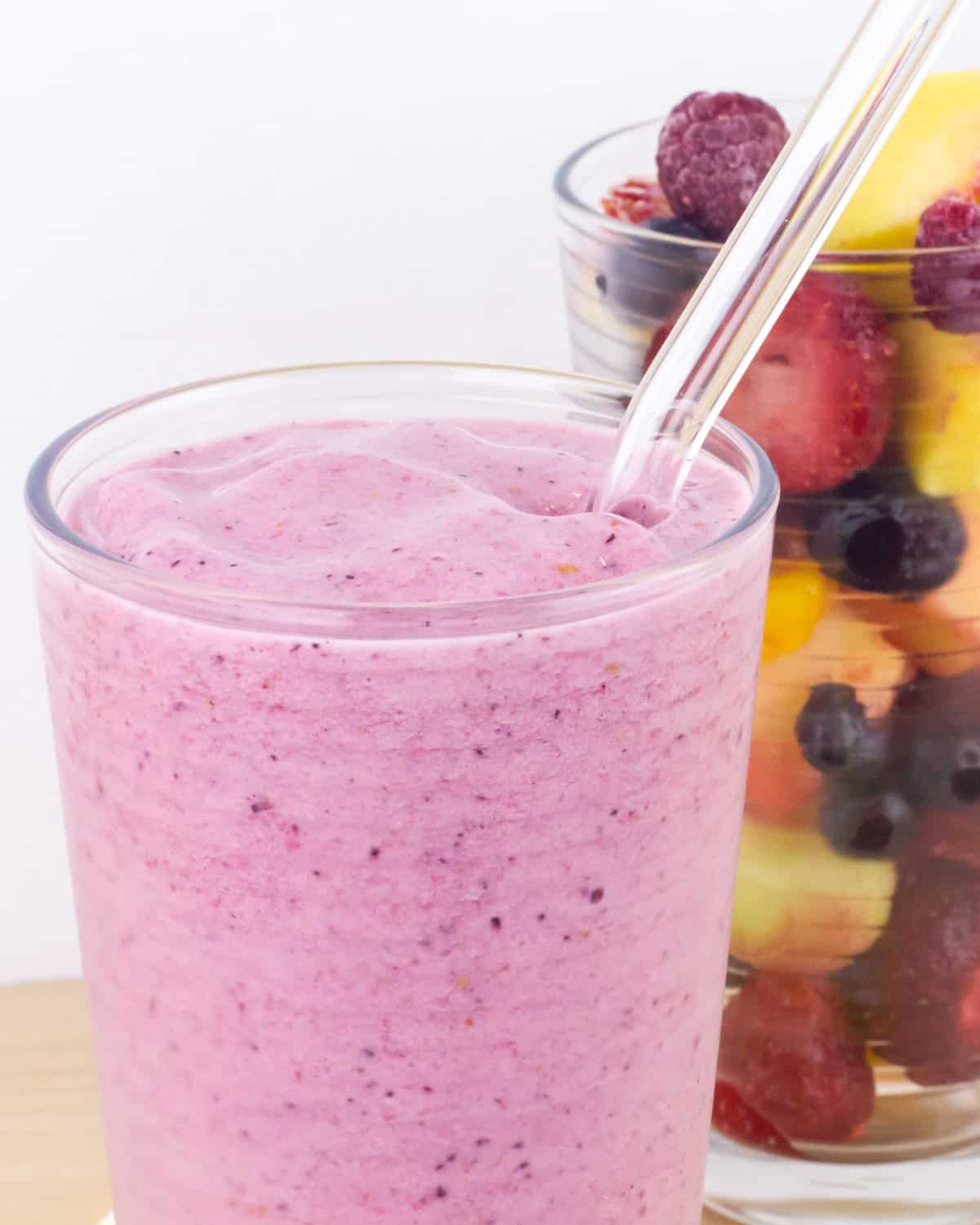 A close up picture of a smoothie with a glass straw.