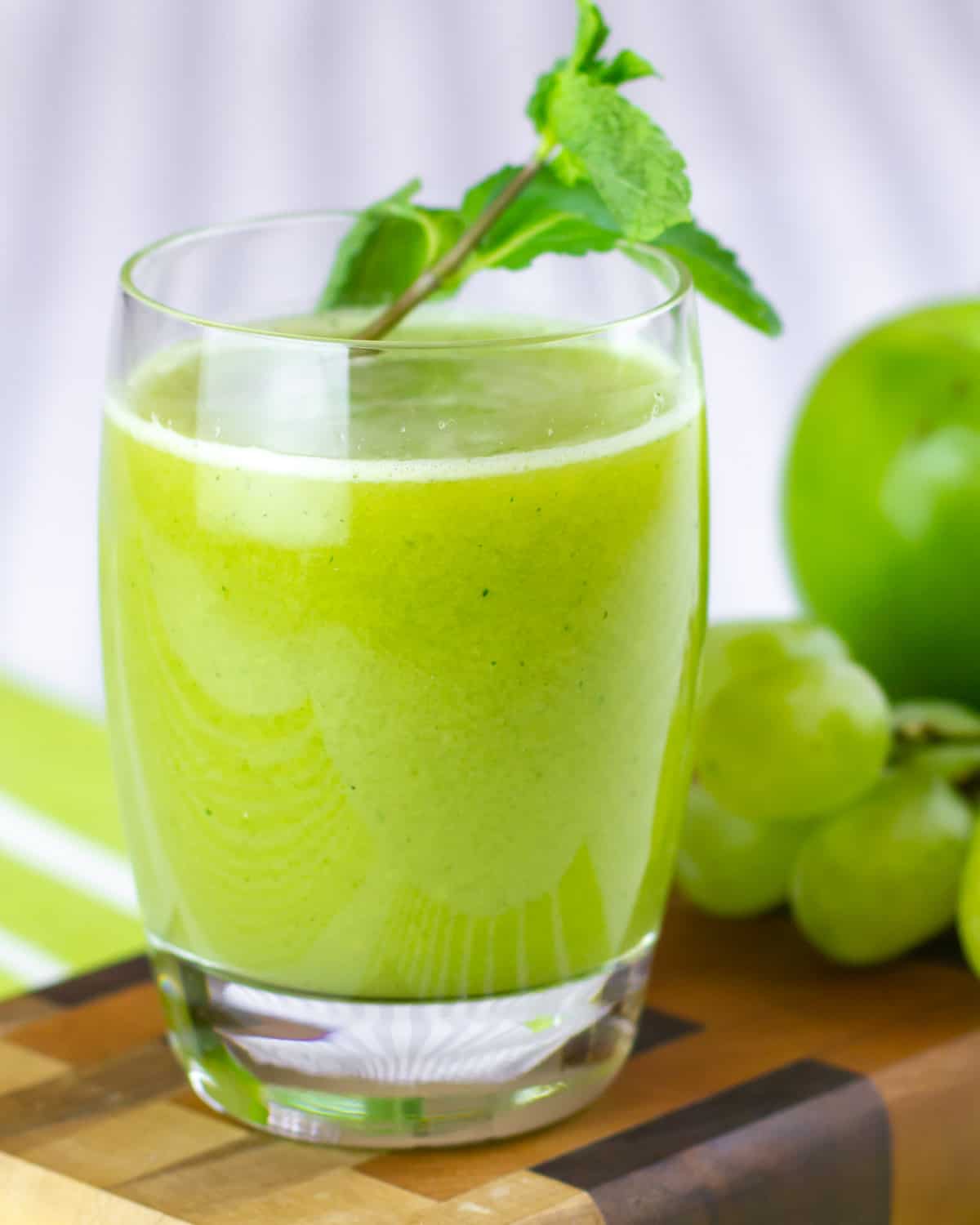 A close up picture of a glass of juice with a sprig fresh mint stuck in the juice.