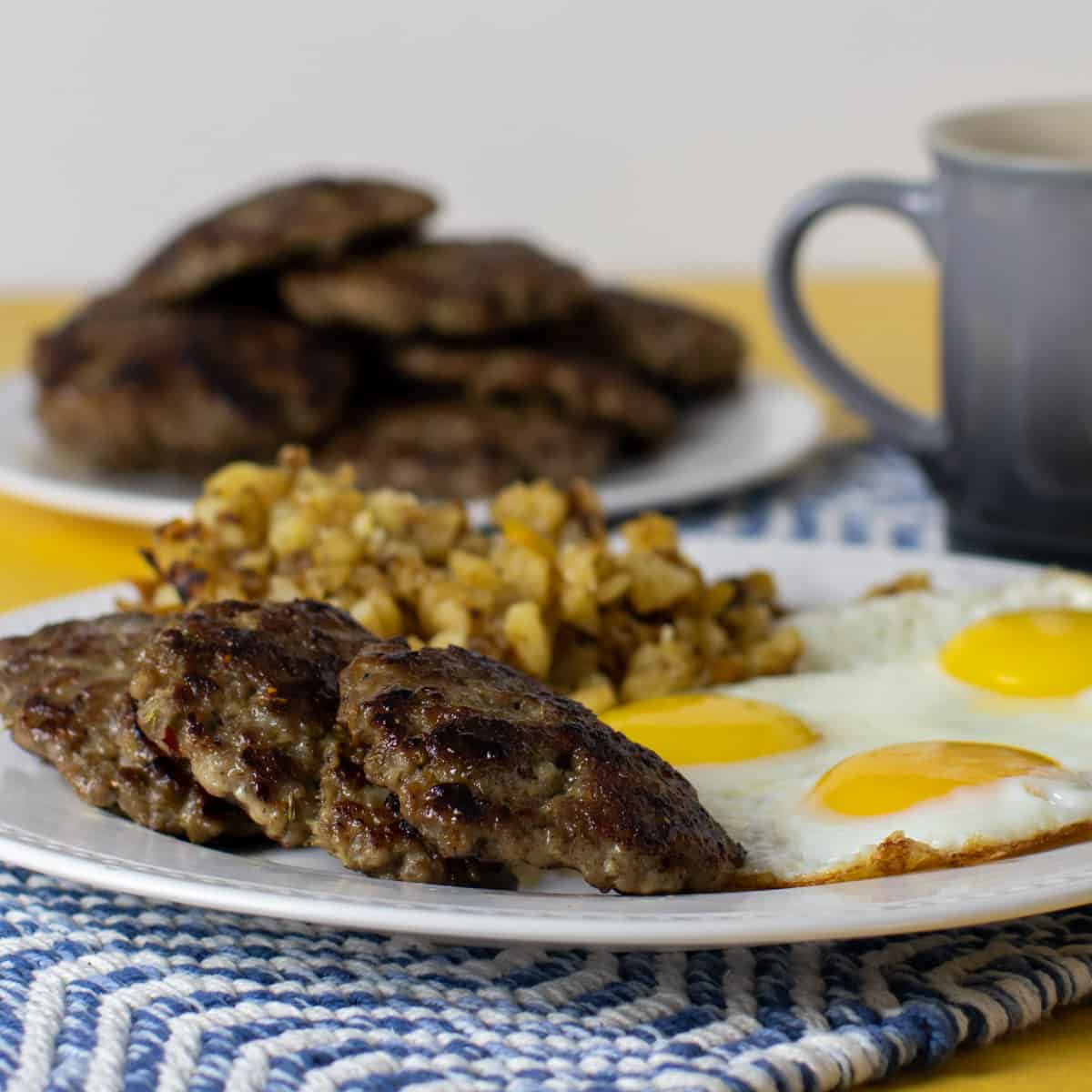 A plate of sausage patties, eggs and hash browns.
