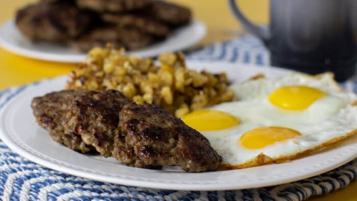 A plate of sausage patties, eggs and hash brown potatoes.