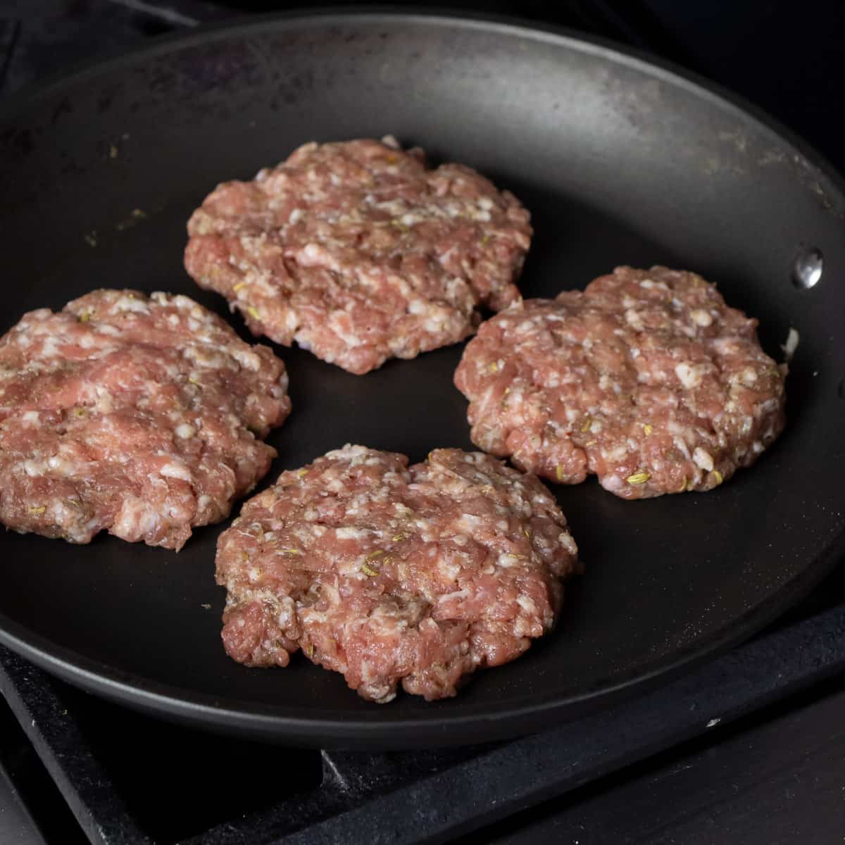 Raw sausage patties in a skillet.