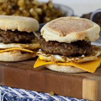 Two breakfast sandwiches on a board of wood.