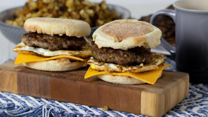 Two breakfast sandwiches on a board of wood.