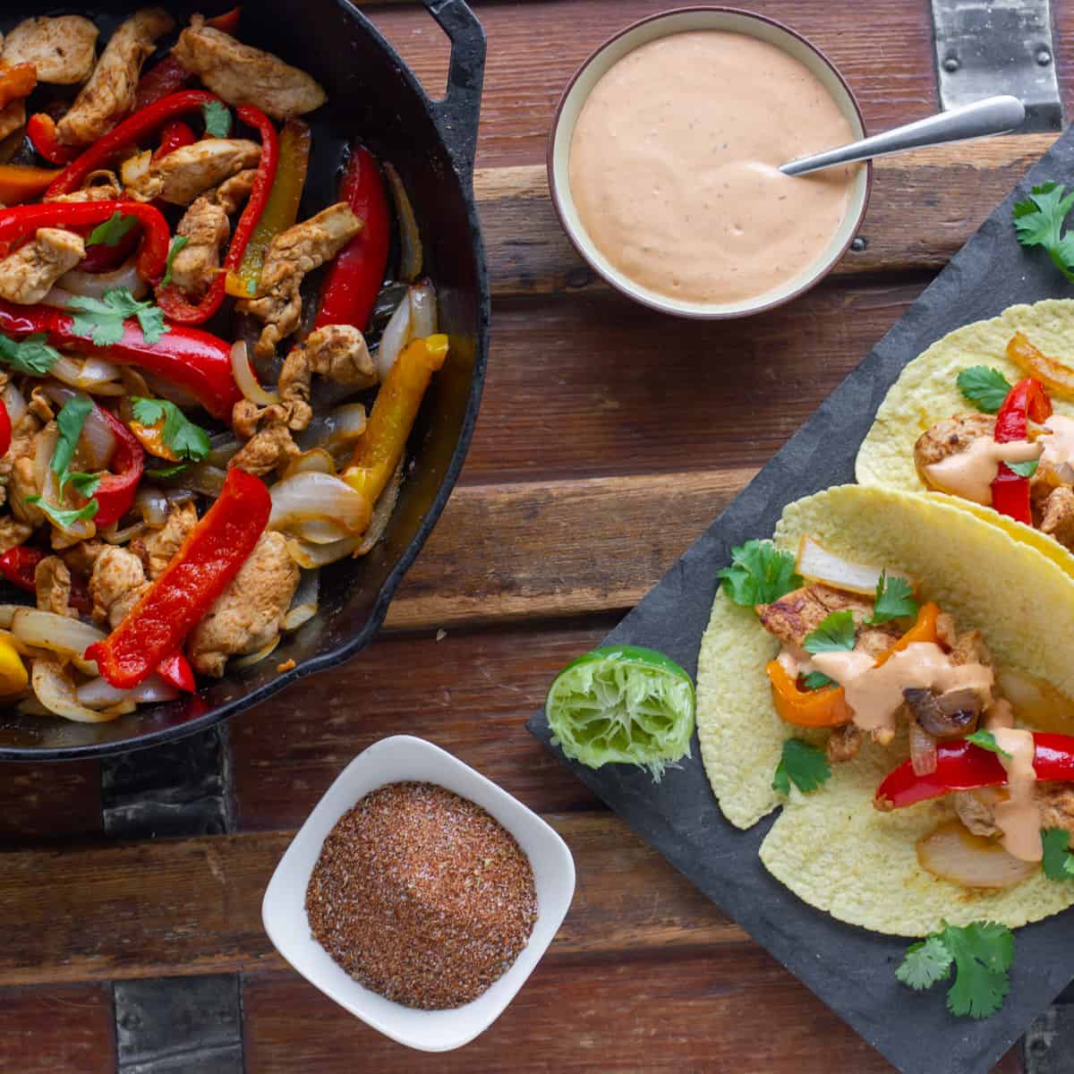 Overhead picture of a bowl of spices, a bowl of cream sauce and a pan of chicken and peppers.