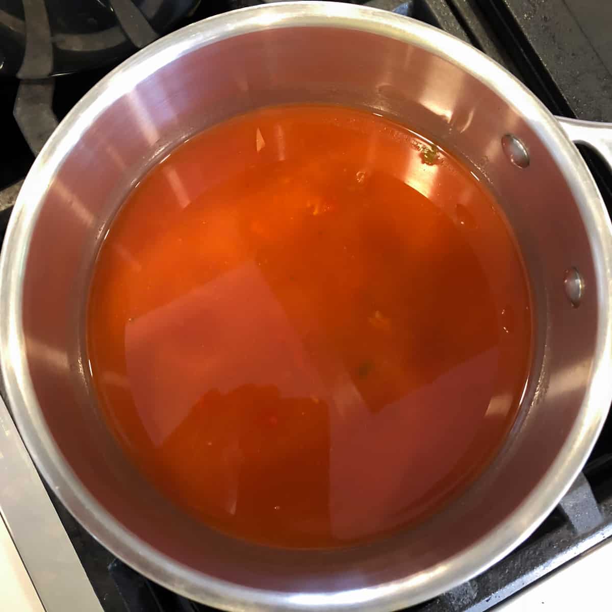 A pot with salsa water and rice simmering.