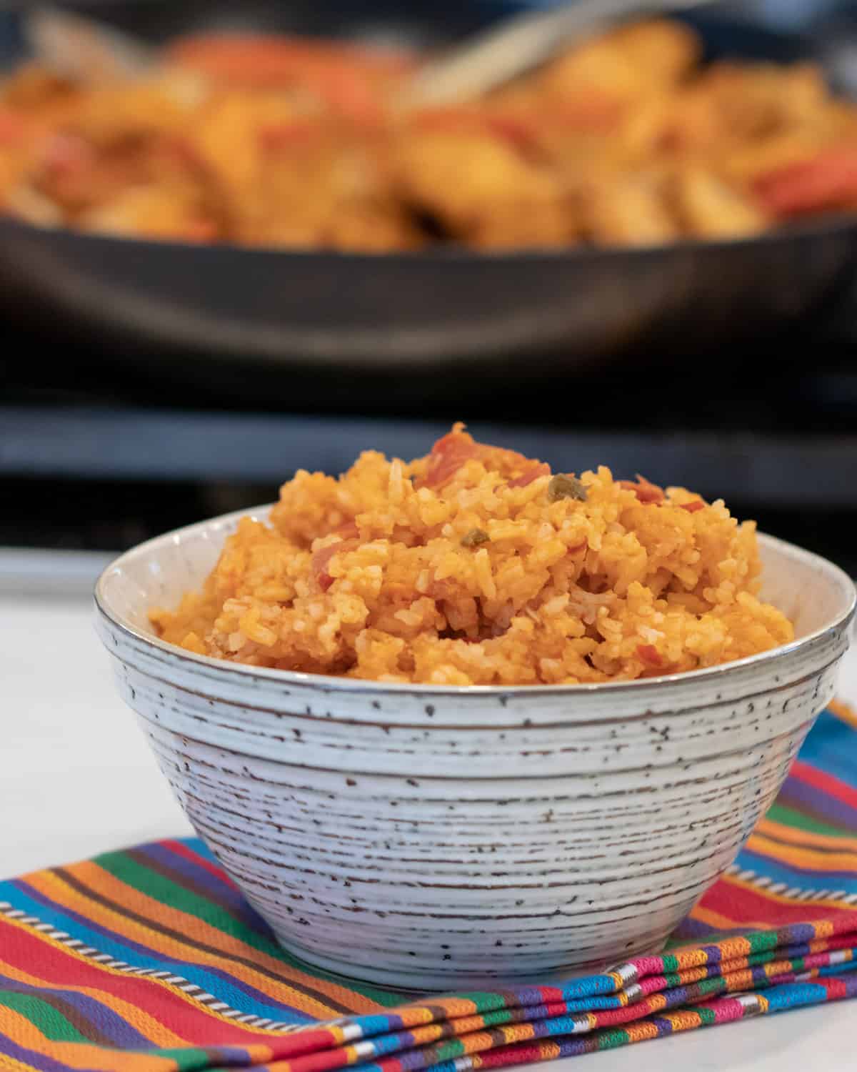 A bowl of rice in front of a skillet.