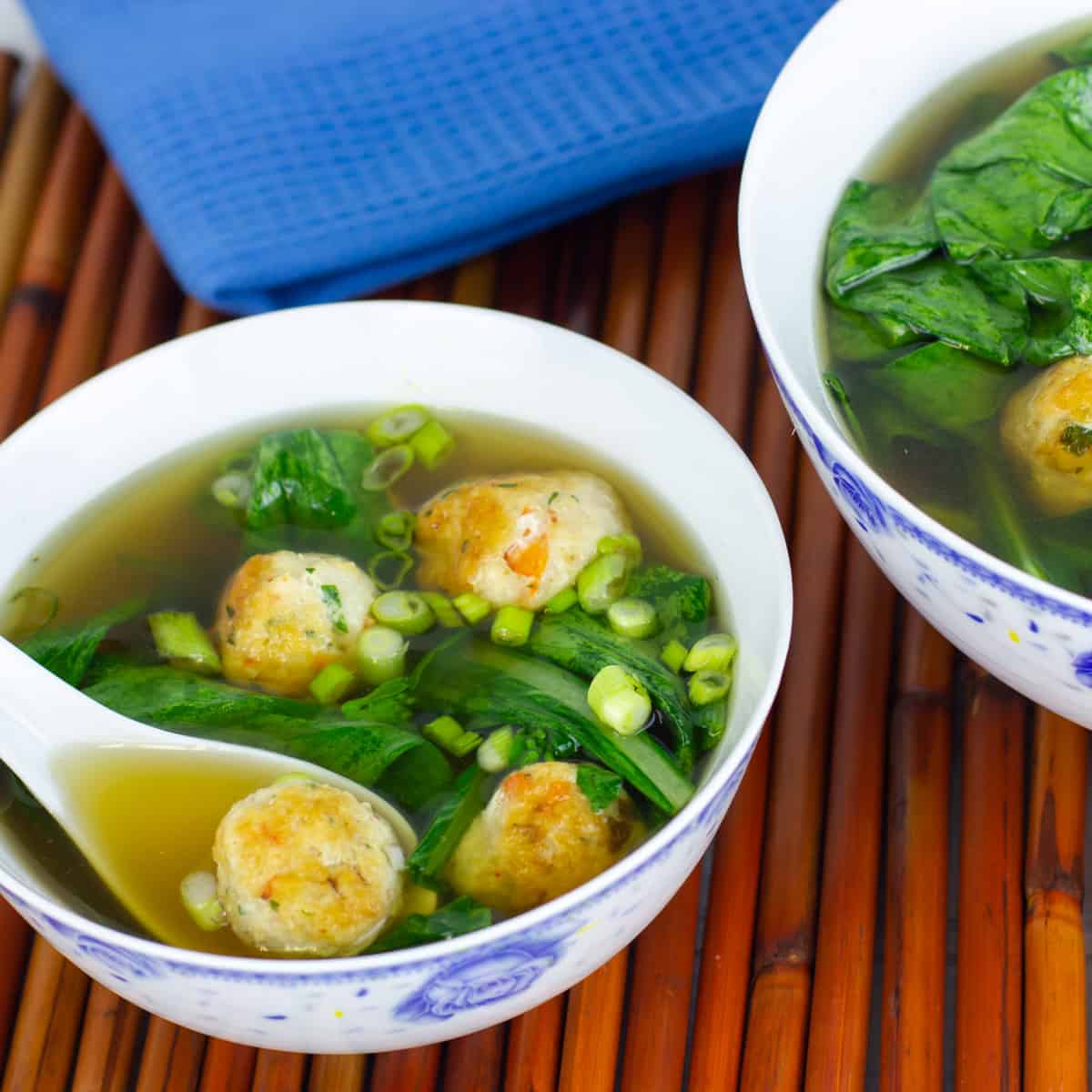 A bowl of soup with meatballs and Chinese greens