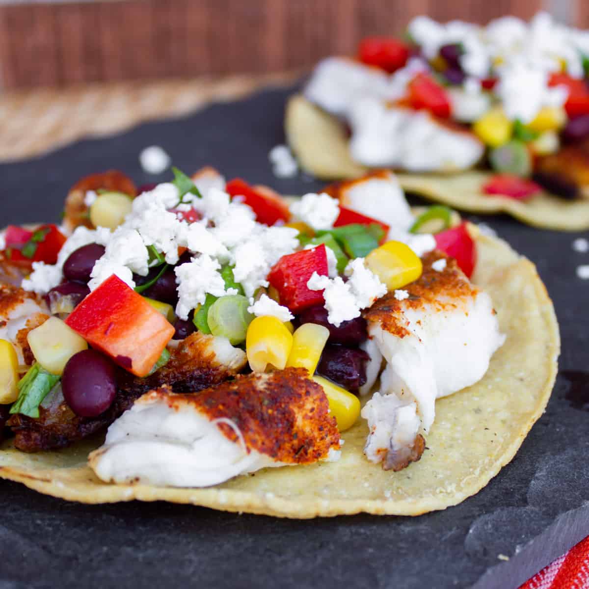 Grilled fish, crumbled feta and other ingredients on a hard corn tostada.