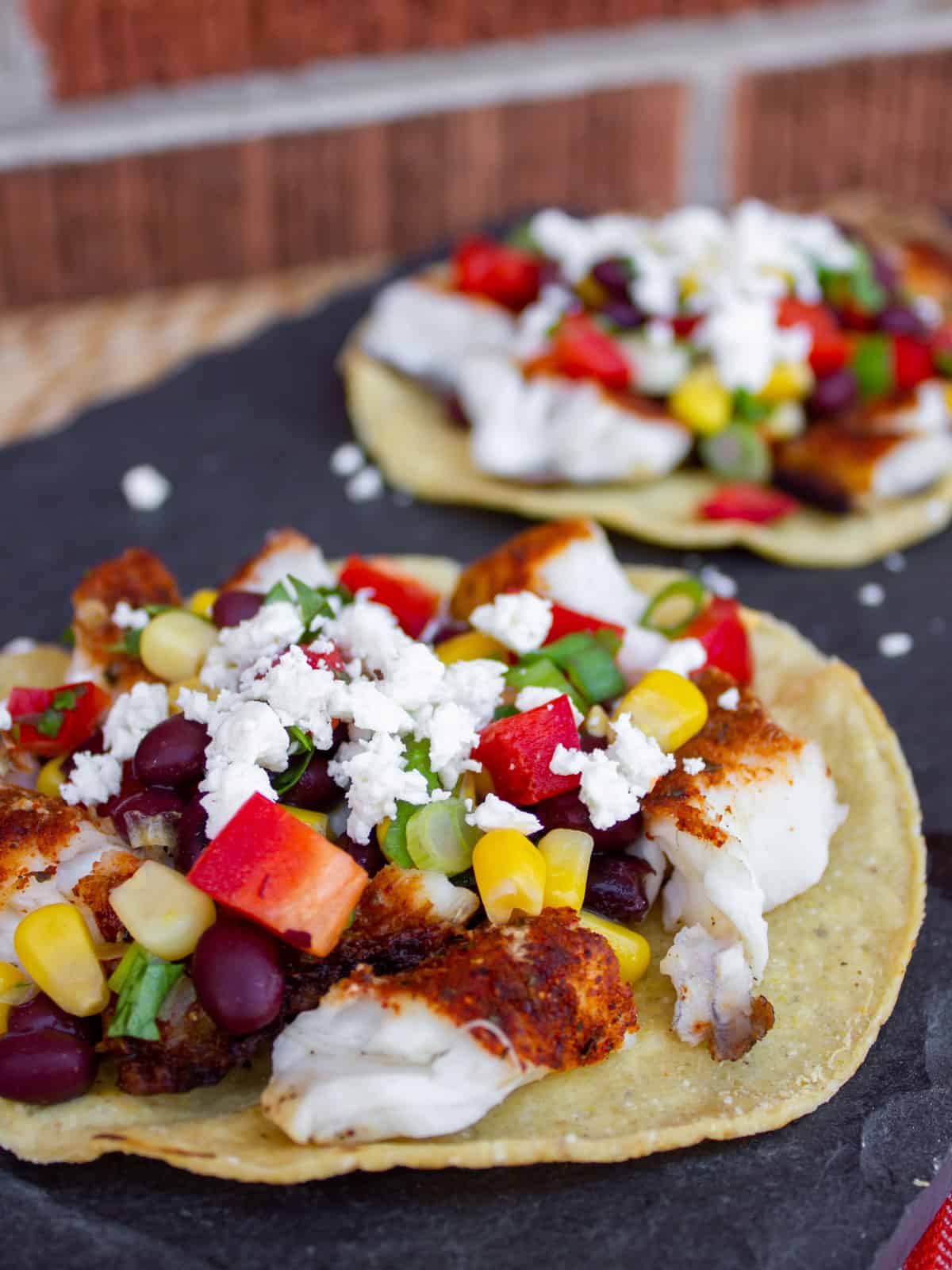 Corn tostada with fish, corn, black beans and more toppings.