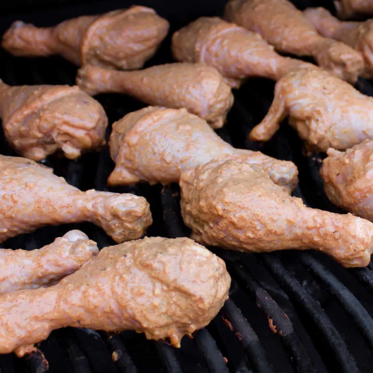 Raw seasoned chicken on grill grates.