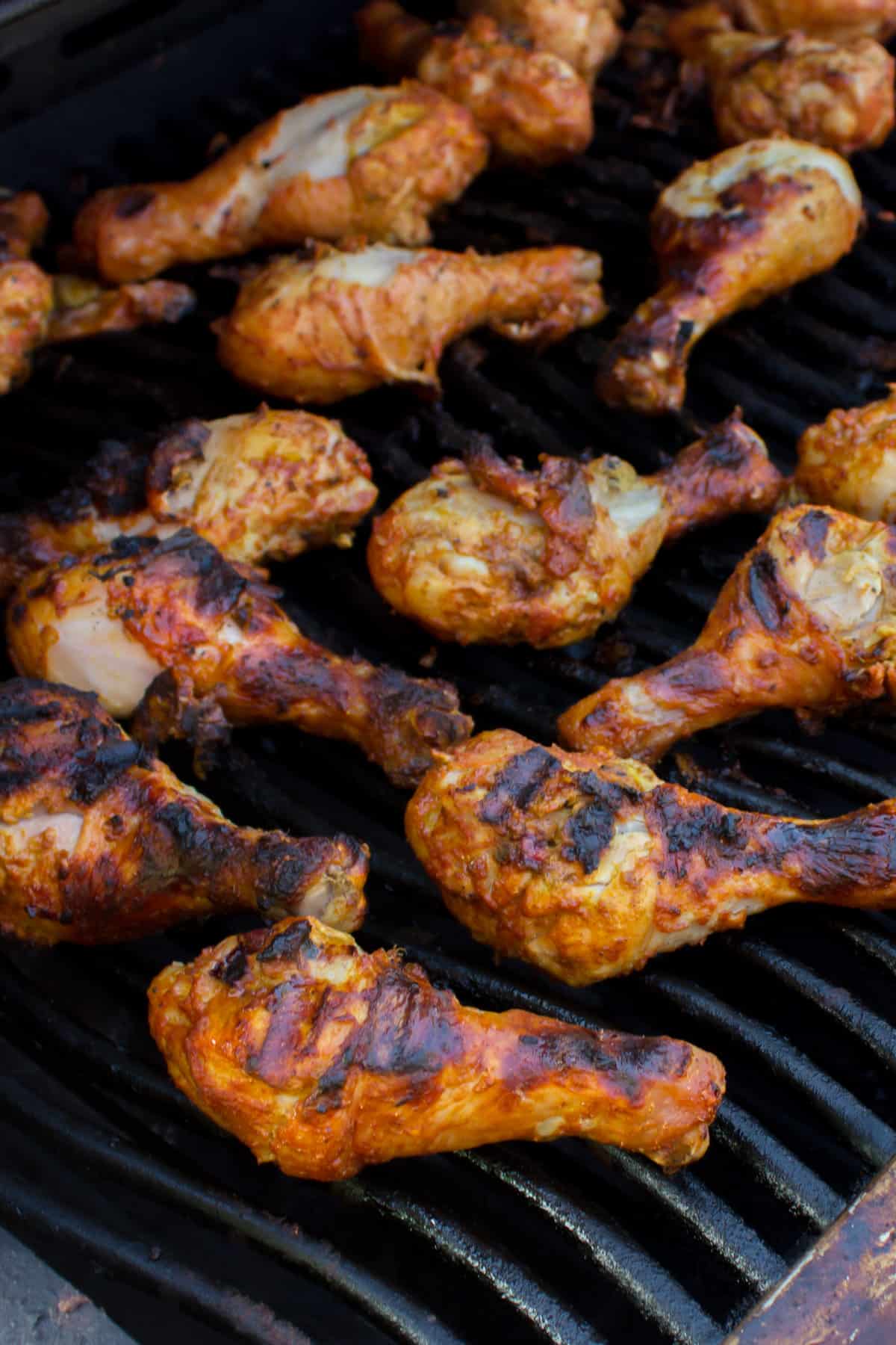 Seasoned chicken drumsticks on a grill.