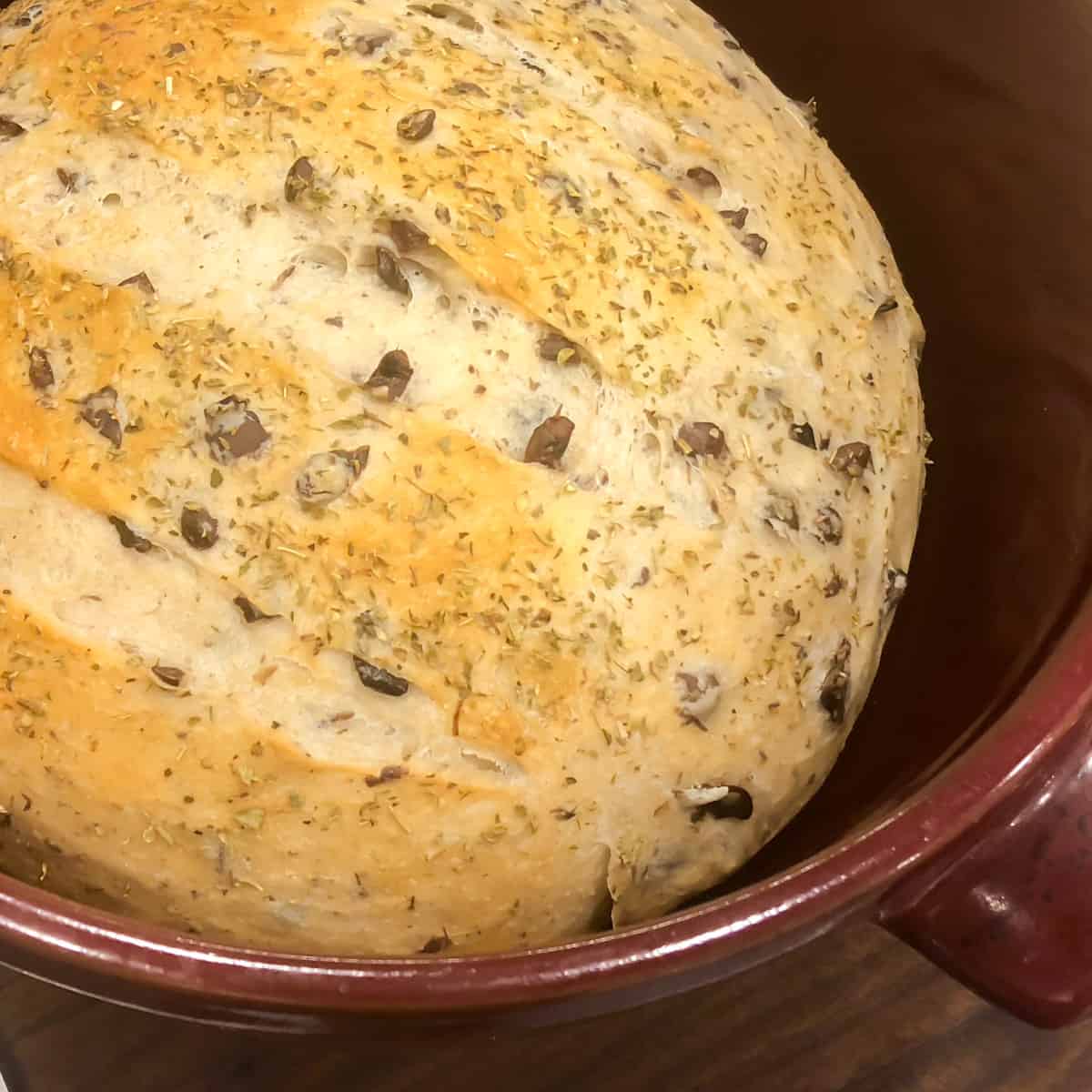A red dutch oven with a bread baked bread inside.