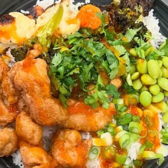 A bowl of rice, fried chicken and vegetables.
