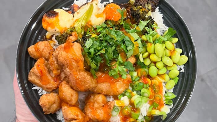 A bowl of rice, fried chicken and vegetables.