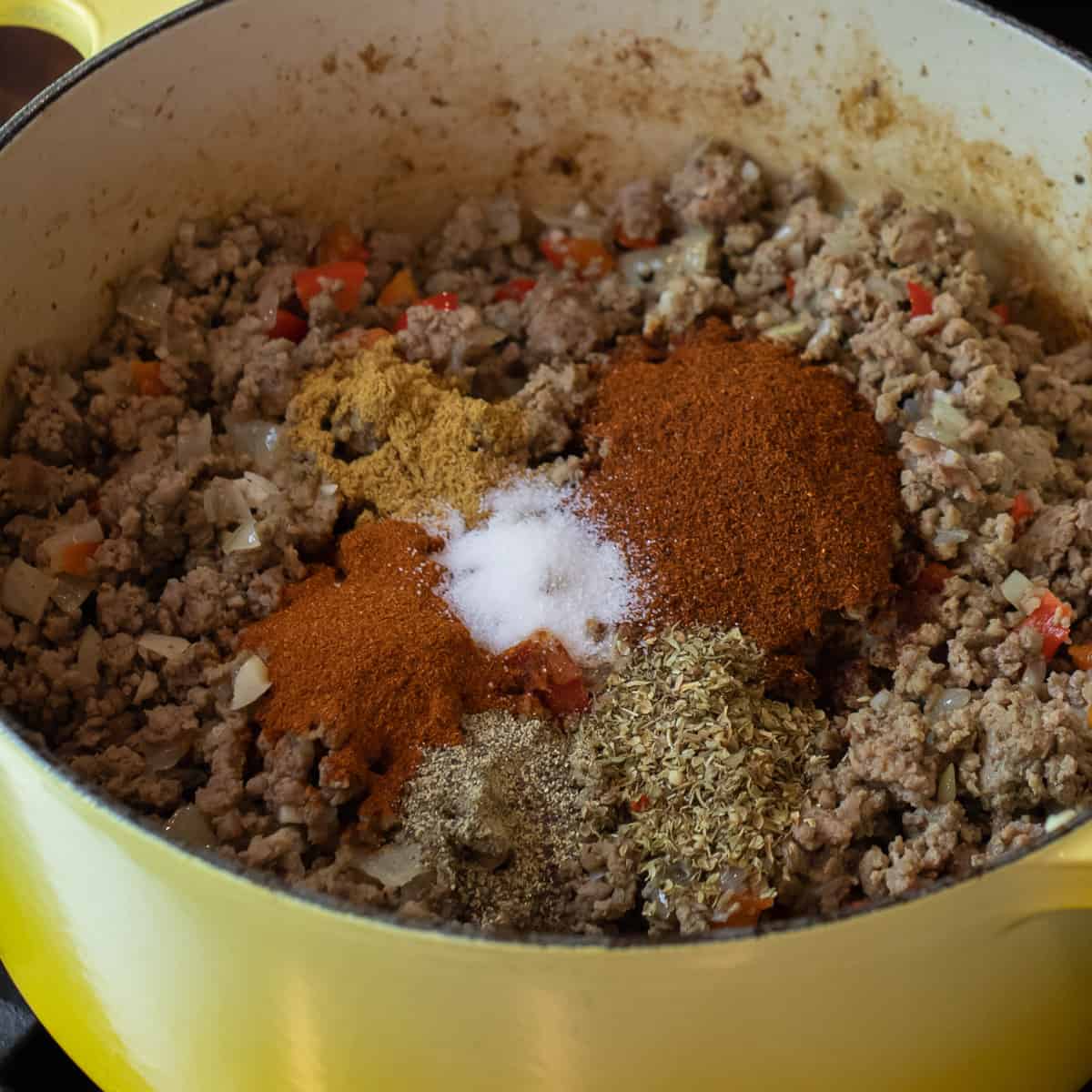 Spices placed on top of browned ground beef.