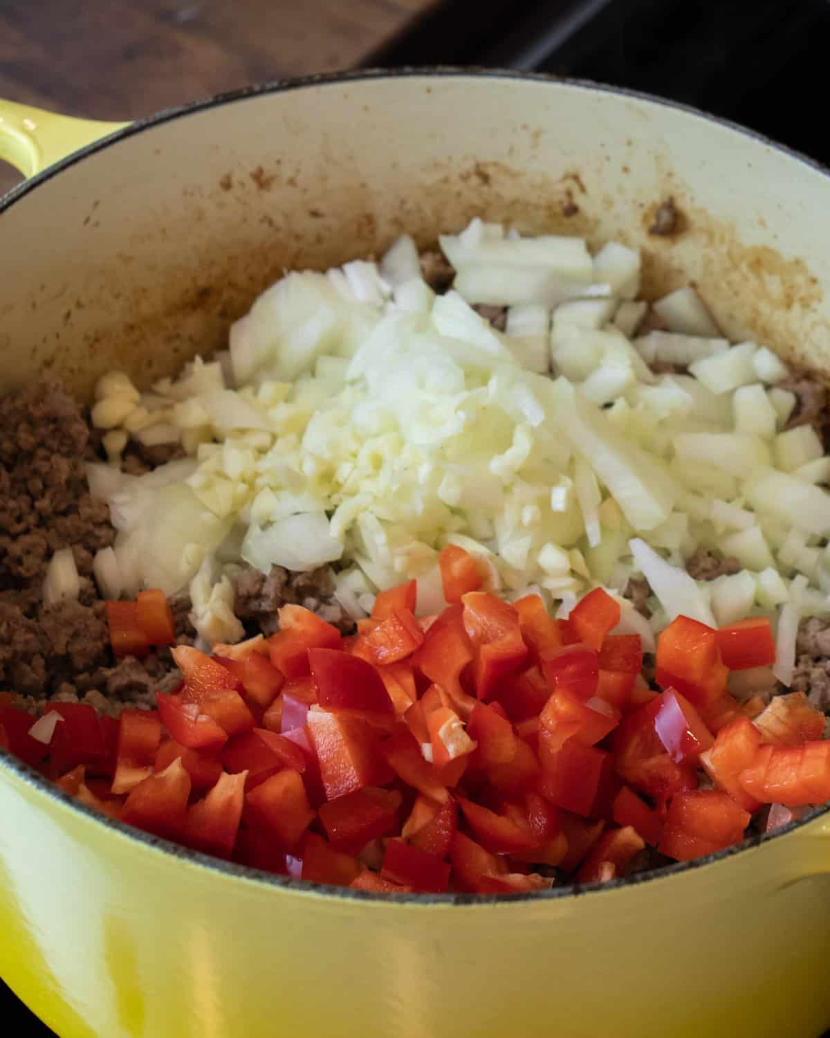 Diced onions and peppers on top of browned ground beef.