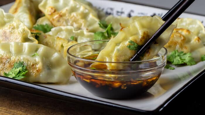 Close up picture of a dumpling dipped in sauce.