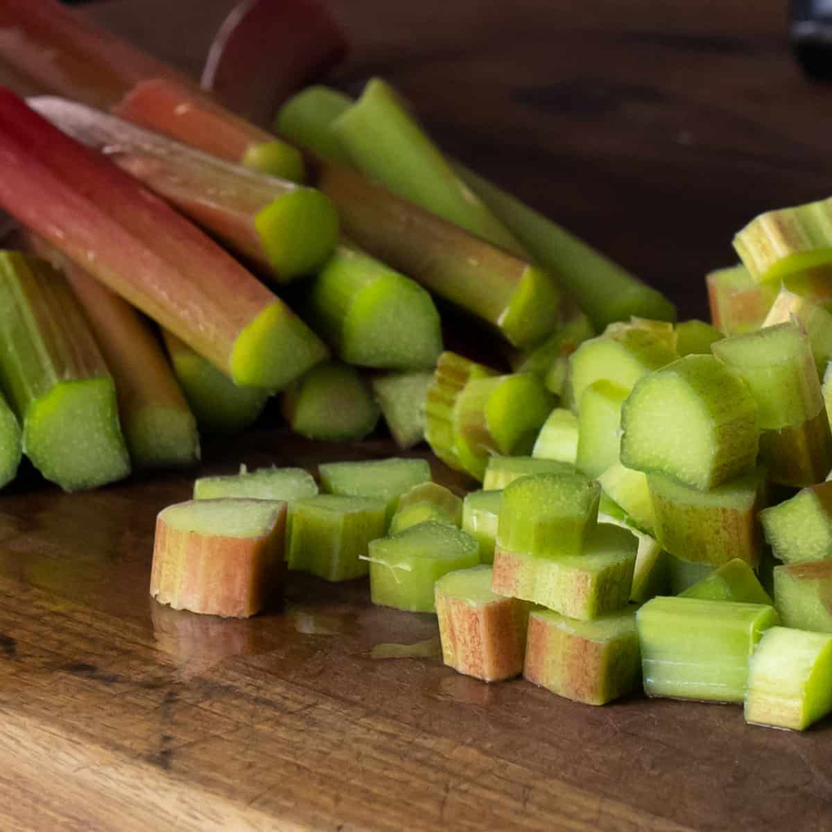 Rhubarb stalks on a cutting board with a piled of chopped pieces.