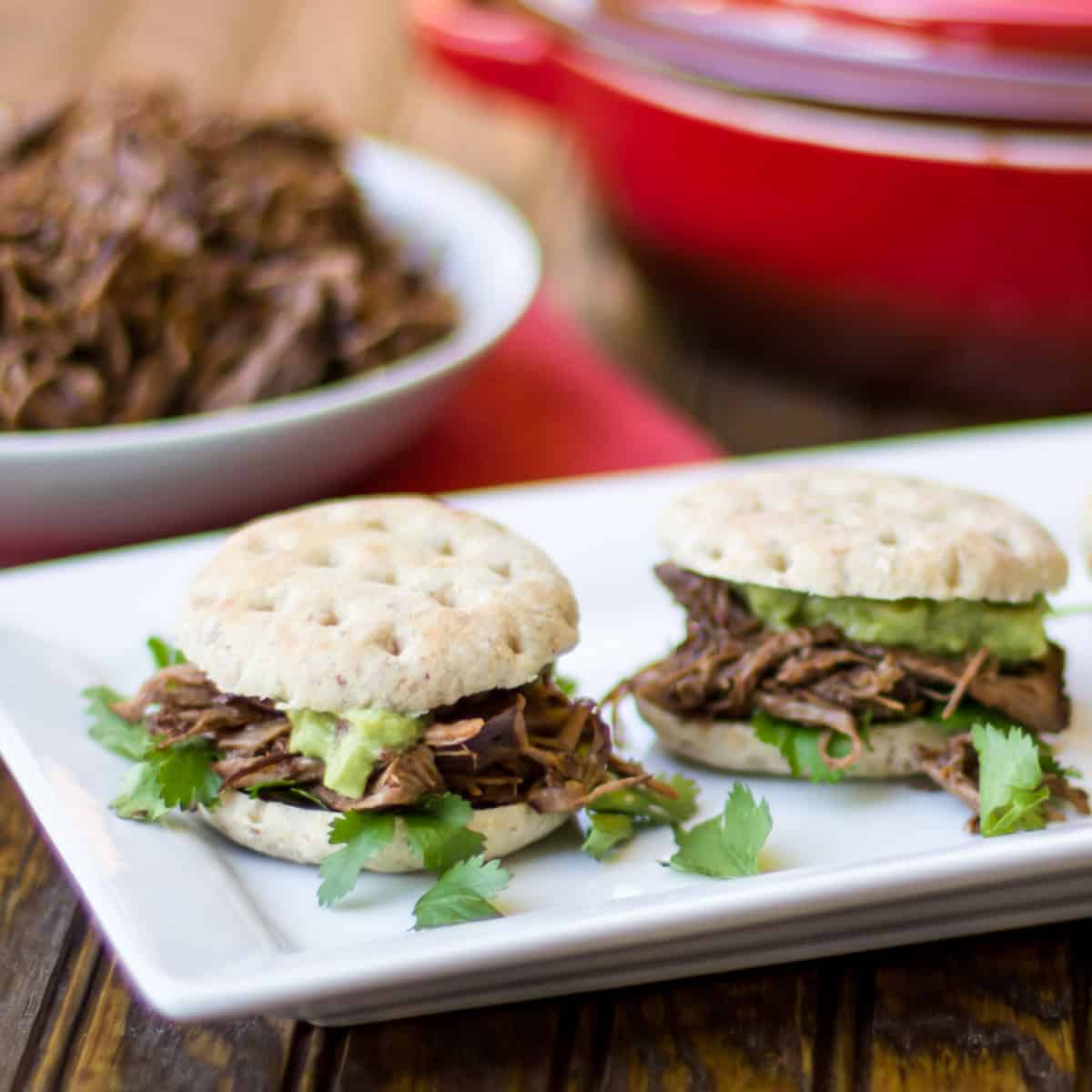 Close up picture with sliders of beef and guacamole.