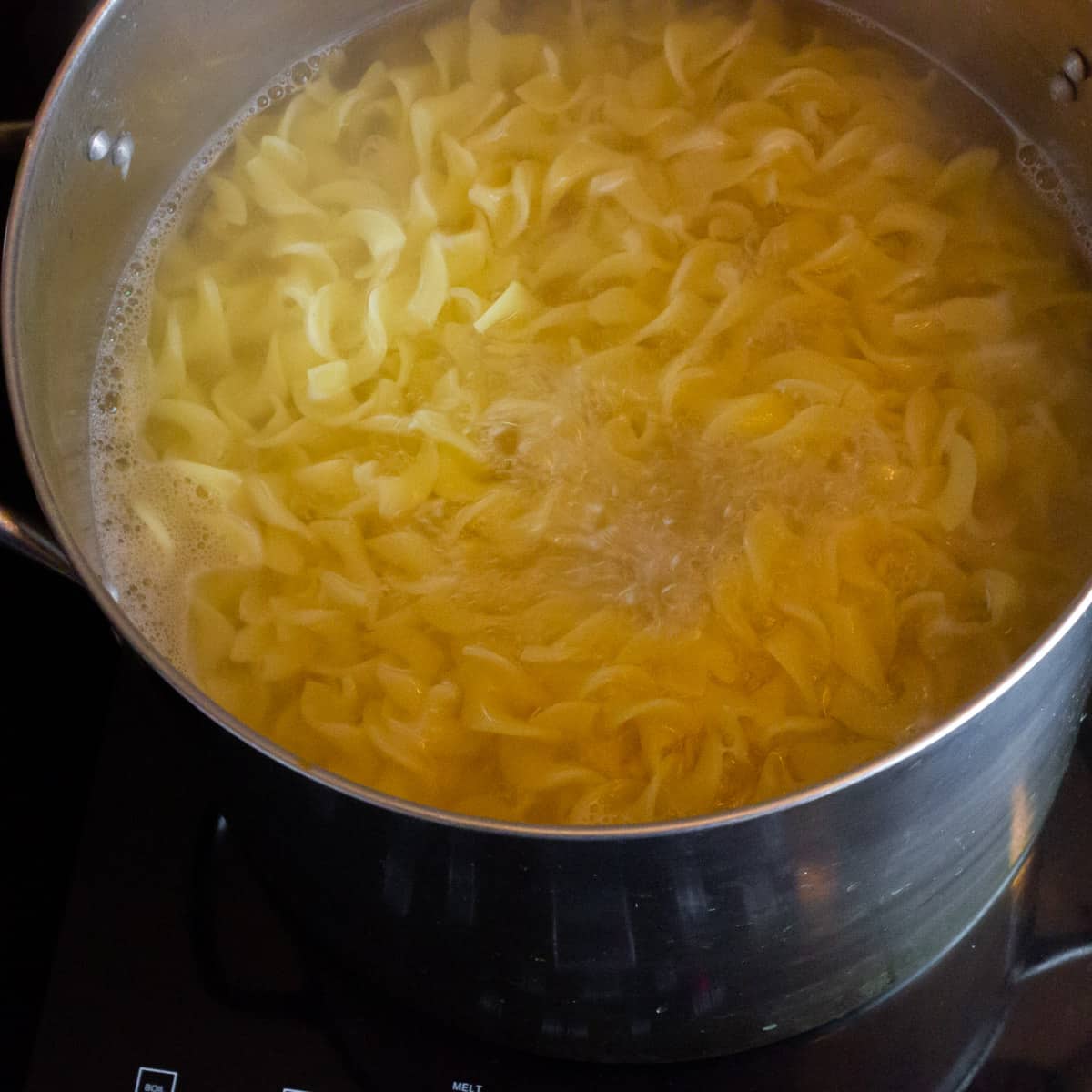 A pot of egg noodles cooking.