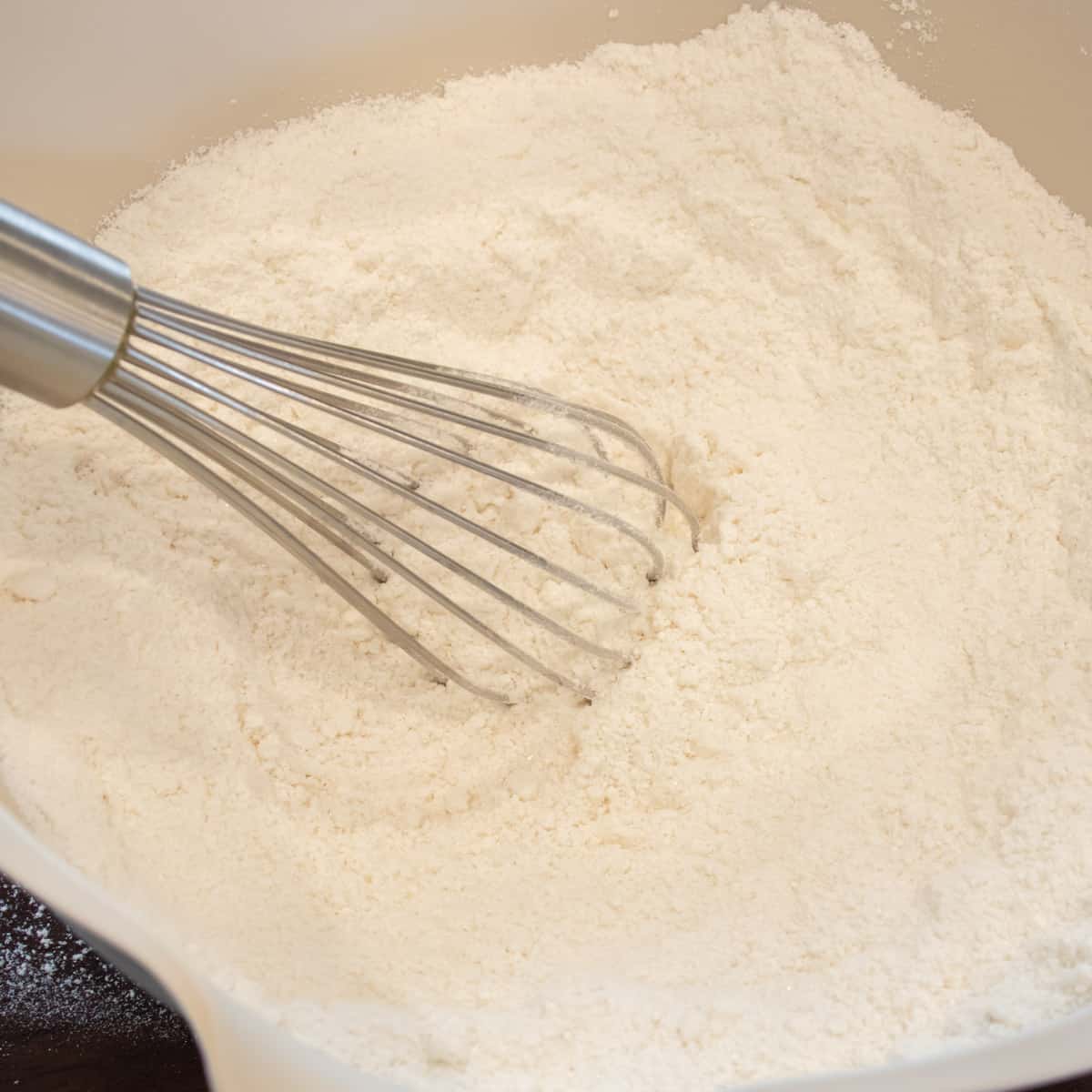 Flour and other dry ingredients whisked together in a mixing bowl.