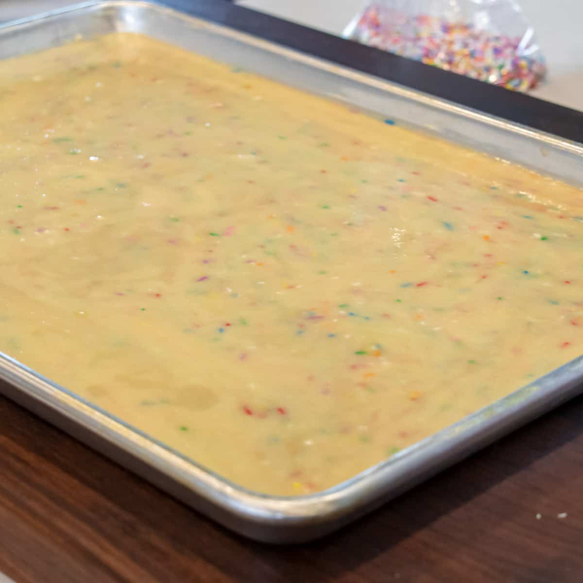 Cake batter poured into a baking sheet and ready to go into the oven.