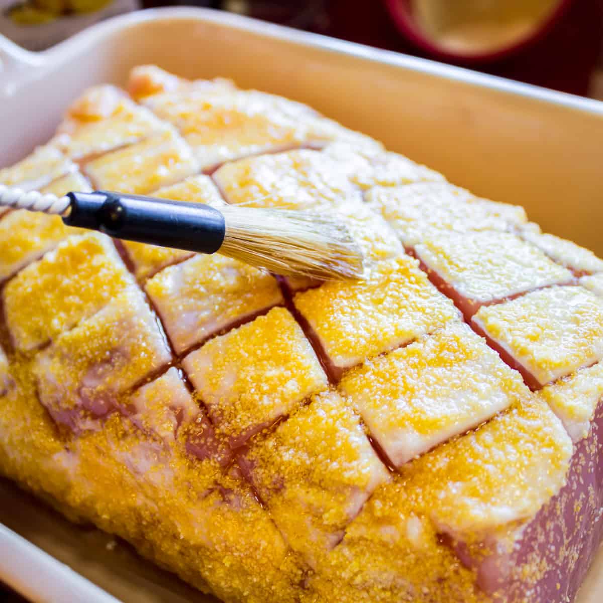 Brushing some maple syrup on an uncooked piece of meat.