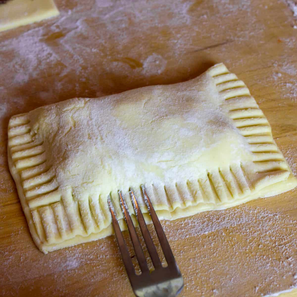 Sealing the sides of a raw turnover with a fork.