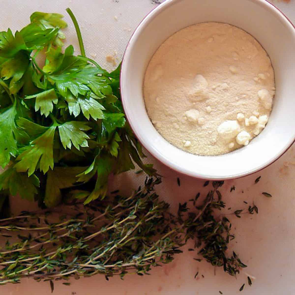 Fresh parsley, thyme and a bowl of Romano cheese.