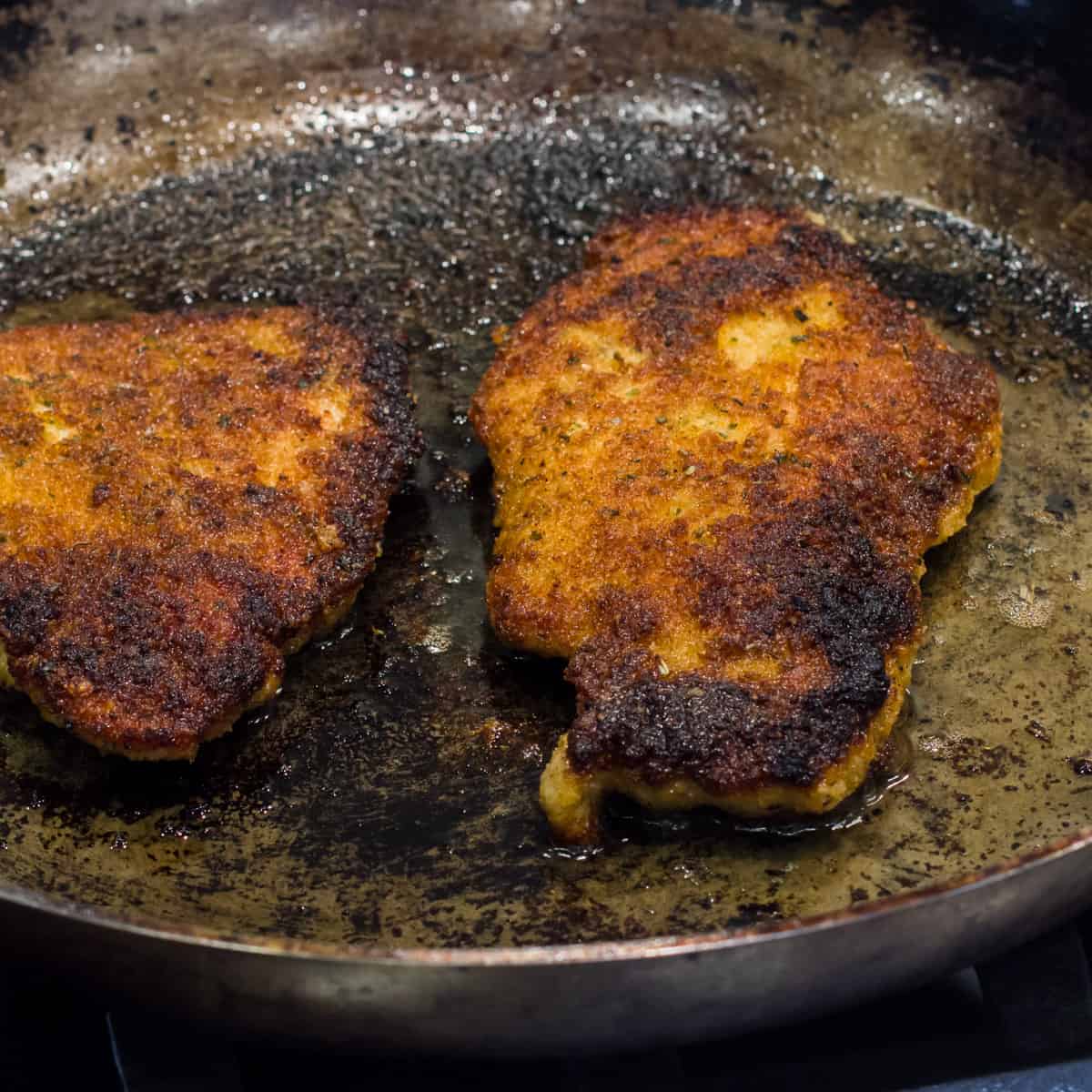 Pork schnitzel in a frying pan.