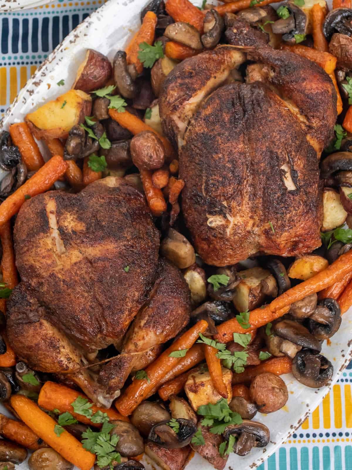 Cooked whole chicken on a platter with vegetables.