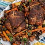 Two cooked whole chicken on platter with vegetables.