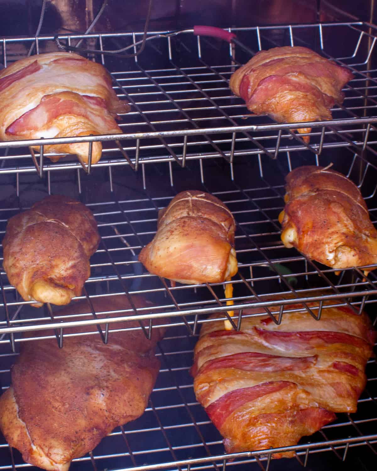 A smoker filled with chicken that have been smoking for a while already.