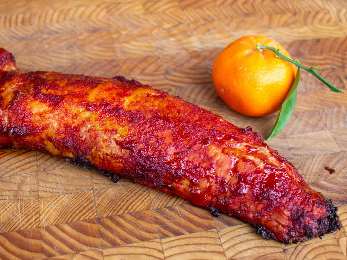 Cooked pork tenderloin next to a tangerine